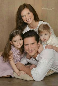 a man, woman and two children are posing for a photo in front of a brown background