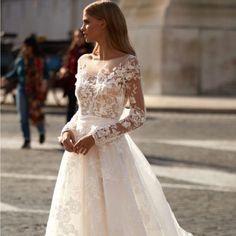 a woman in a wedding dress standing on the street