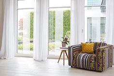 a living room filled with furniture and white curtains