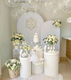 a table topped with lots of white cakes and vases filled with flowers next to each other