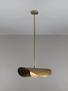 a modern light fixture hanging from the ceiling in a room with grey walls and flooring