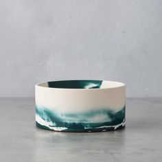 a white and blue bowl sitting on top of a table next to a wall with a gray background