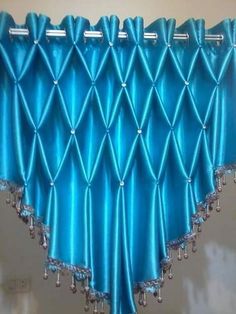 a blue curtain hanging from the side of a window with beaded trim on it