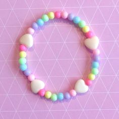 a bracelet made out of plastic beads and pastel colors on a pink background with white triangles