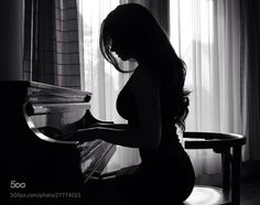 a pregnant woman is playing the piano in her home studio, black and white photo