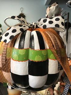 a pumpkin decorated with black and white stripes, polka dots and green ribbon is sitting on a table