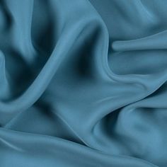 a close up view of a blue fabric with very soft folds and smooth lines on it