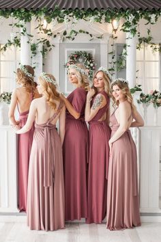 the bridesmaids are dressed in dusty pink dresses and floral head wreaths on their heads