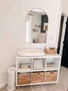 there is a white shelf with baskets on it and a mirror in the corner behind it