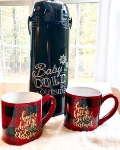 two coffee mugs sitting on top of a white rug next to a black bottle