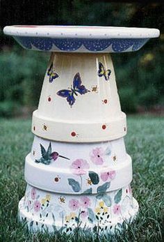 a birdbath sitting on top of a lawn covered in flowers and butterfly designs