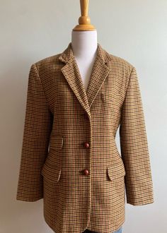 Here is a "Banana Republic" menswear jacket from the early 1990's. All wool, it is woven in a houndstooth check in toffee/red/black/olive on a tan ground. The jacket is tailored to be slightly fitted like an equestrian jacket with curved sides and body darts, both front and back. The back has curved seams as well.  There is a three button closure and a regular notched jacket collar and lapels.  There are a total of four pockets in front: a breast pocket with a band top and three pockets with rounded flaps. All pockets are "working" ones. Sleeves are long with three buttons at cuff. Fully lined in rayon. Jacket is in fabulous condition with no stains, holes, rips, odors etc. Size on label is a four, but will fit a larger size. Please refer to dimensions below and compare to a tailored jacke Menswear Jacket, Equestrian Jacket, Check Jacket, Jacket Collar, Checked Jacket, Banana Republic Women, A Banana, Black Olive, Tailored Jacket