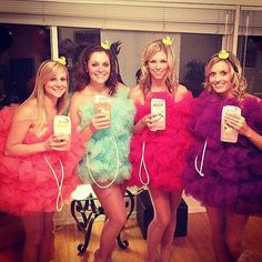 four beautiful women dressed in colorful dresses holding cell phones and posing for a photo together