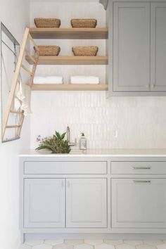 a white kitchen with gray cabinets and shelves