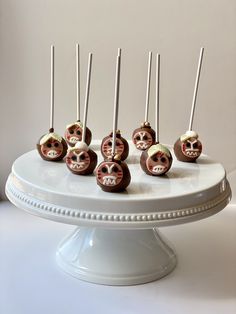 chocolate candies with faces on them sitting on a cake platter, ready to be eaten