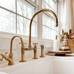 a kitchen sink with brass faucets and soap dispenser