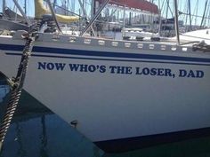 a white boat with blue writing on it's side docked at a dock in the water