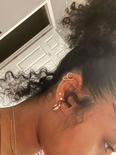 a close up of a person with ear piercings on her head and hair in the background