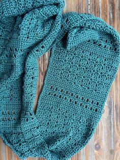 a green crocheted scarf laying on top of a wooden floor