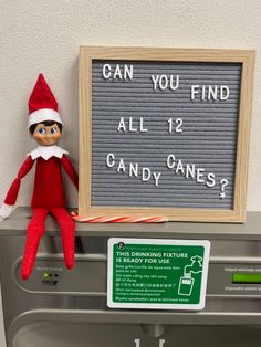 an elf sitting on top of a washing machine next to a sign that says can you find all 12 candy canes?