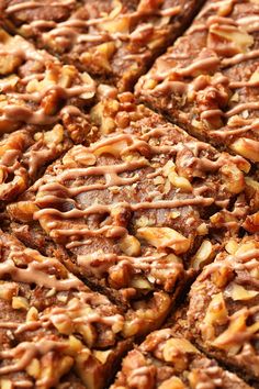 a close up view of some brownies with nuts on top and drizzled in chocolate