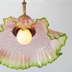 a pink and green flower shaped light hanging from a ceiling fixture with a white wall in the background