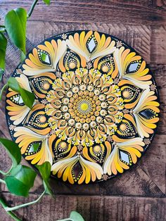 a yellow and black plate sitting on top of a wooden table next to green leaves