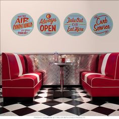 three red chairs sitting next to each other in front of a wall with advertisements on it