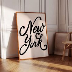 a new york sign sitting on the floor next to a wooden chair and wall in an empty room