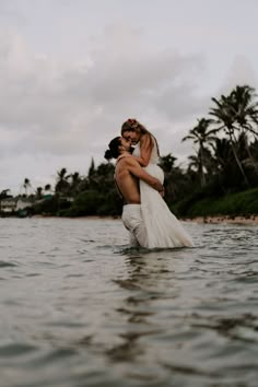 a bride and groom hugging in the ocean