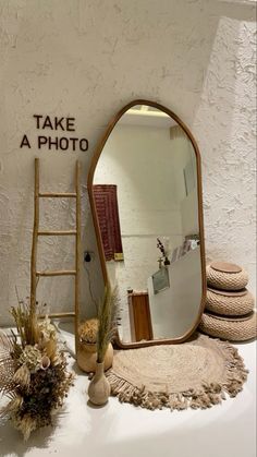 there is a large mirror on the table next to a ladder and vases with plants