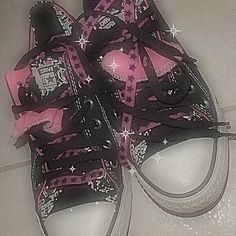 a pair of pink and black converse shoes with stars on the bottom, tied together