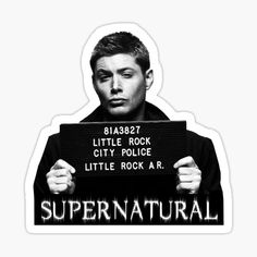 a man holding a sign with the words supernatural written on it in black and white