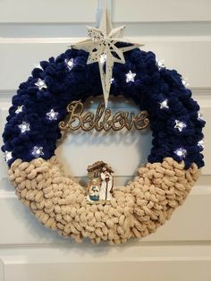 a christmas wreath hanging on a door with the word believe spelled in gold and blue