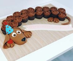 a birthday cake shaped like a dog with cupcakes in the shape of it