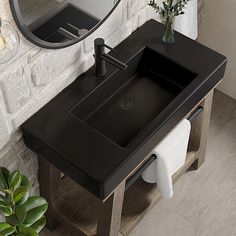 a bathroom sink sitting under a mirror next to a plant