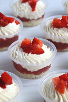 small desserts with strawberries and whipped cream in plastic cups on a white table