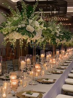 a long table with white flowers and candles on it is set up for a formal function