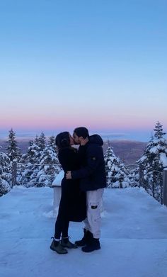 two people standing in the snow kissing each other