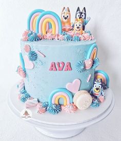 a blue cake decorated with cartoon characters and rainbows