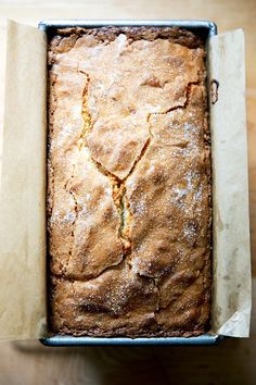 a loaf of bread sitting in a pan on top of a wooden table next to a knife