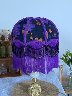 a table topped with a purple lamp shade