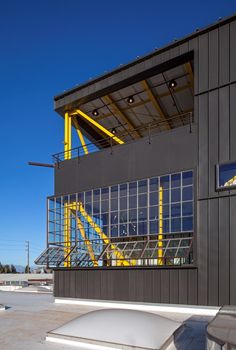 a skateboard ramp in front of a building with glass windows and yellow railings