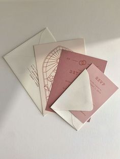 three envelopes are stacked on top of each other, one has a pink and white design