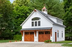 a large white barn with two brown garage doors