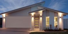 a white house with two lights on it's front door and side windows at night