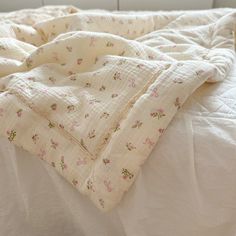 an unmade bed with white sheets and pink flowers