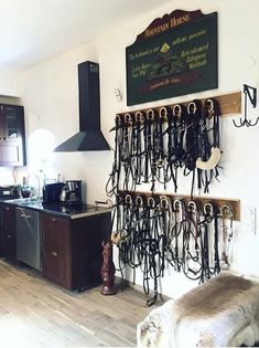 there are many horse bridles hanging on the wall in this room with wood flooring