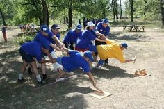 a group of people in blue shirts and white caps are playing with a baseball bat