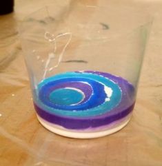 a blue and purple object sitting on top of a wooden table next to a plastic cup